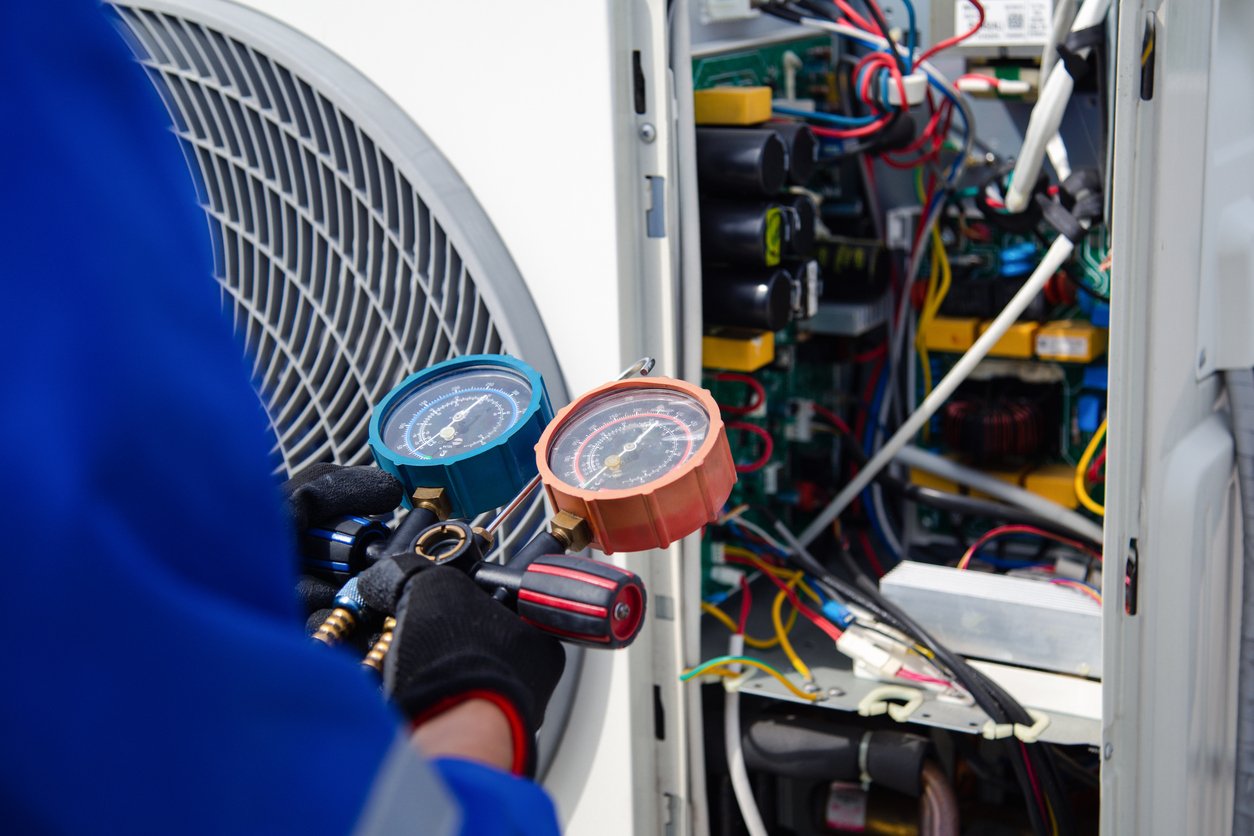 air conditioner service .the air conditioner technician is using a gauge to measure the refrigerant pressure. air compressor.